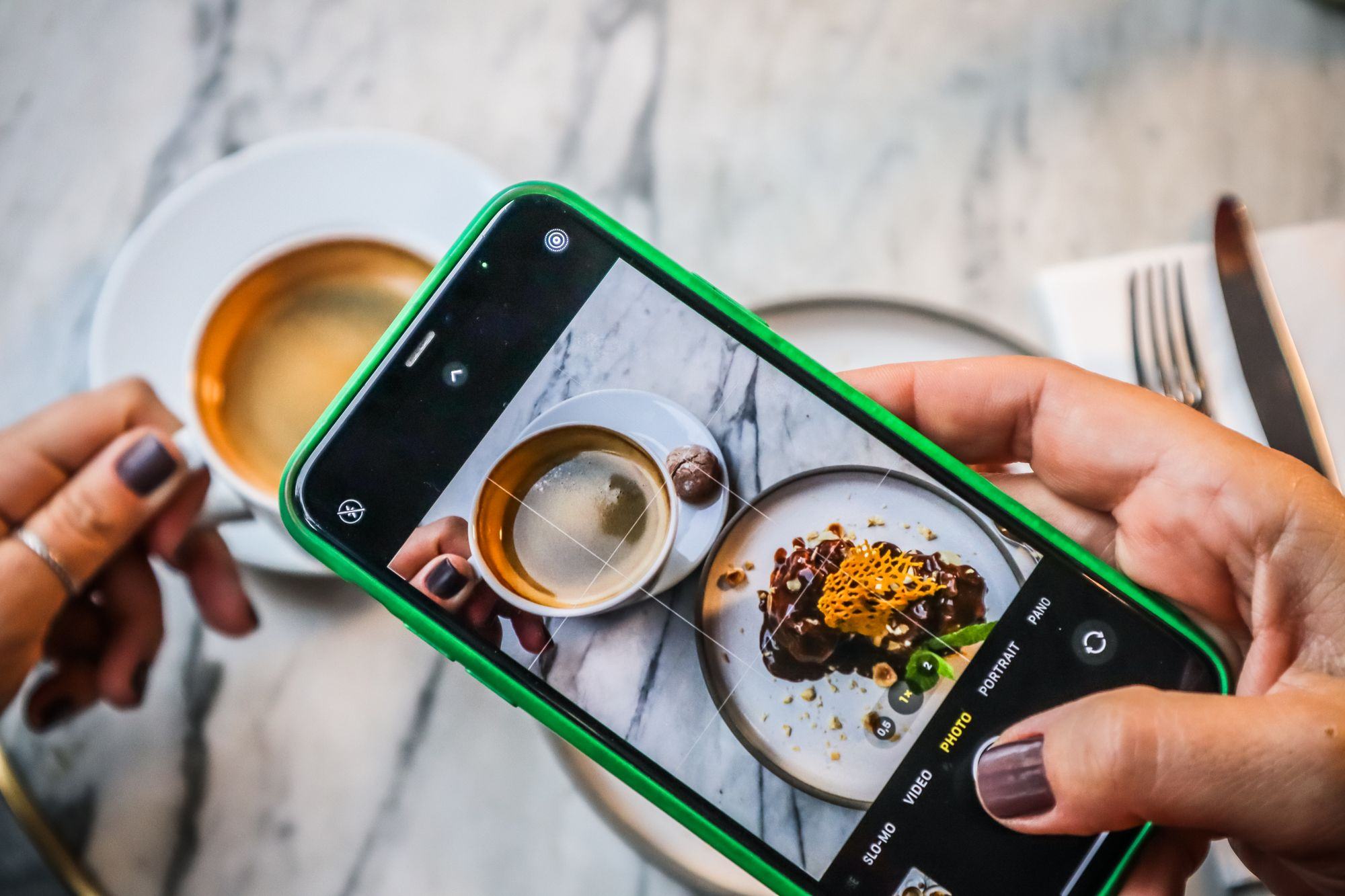 Una persona fotografa un dolce e un caffè con il telefono. Fotografia d’ispirazione.