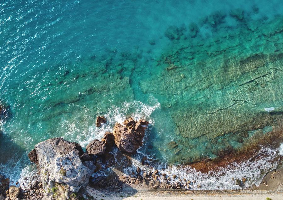 Il mare color acquamarina visto dall’alto, con gli scogli. Fotografia d’ispirazione.