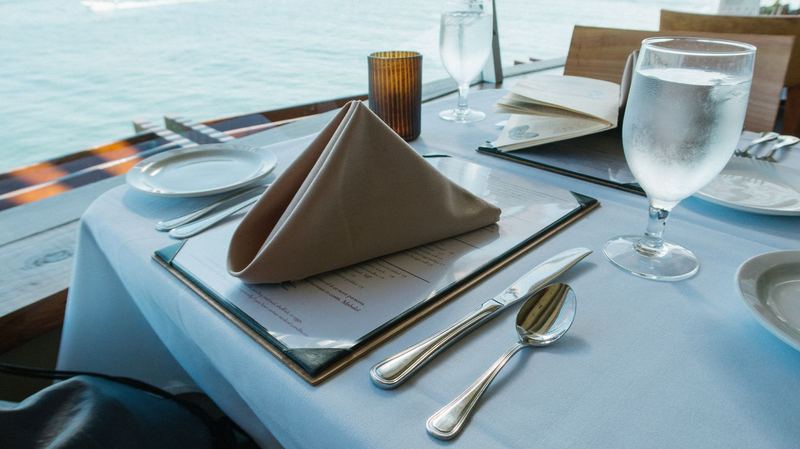 Una tavola apparecchiata con il menu, davanti al mare. Fotografia d’ispirazione.